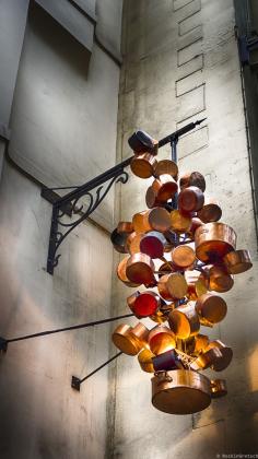 
                    
                        Photograph Hanging Copper pots artistically recreated into an outdoor light fixture at a restaurant in Paris.....by Rockin
                    
                