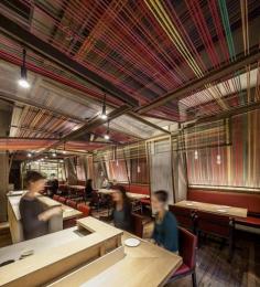
                    
                        Local studio El Equipo Creativo reinterpreted traditional wooden Peruvian cloth-weaving equipment to create angled panels from thick threads stretched across wooden frames. Some of the frames are twined with white cords to contrast with the colourful sections.
                    
                