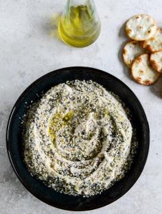 white bean hummus | 3 cups cooked cannellini/great northern beans (or 2 cans, drained and rinsed), 6 tablespoons olive oil + more for drizzling, 2 tablespoons toasted sesame oil, 1 whole head of roasted garlic, 1/4 teaspoon salt, 2 tablespoons dried minced onion, 2 tablespoons toasted sesame seeds, 1 tablespoon poppy seeds, 1 tablespoon dried minced garlic, 1 teaspoon flaked sea salt, 1/4 teaspoon black pepper, crackers for serving.