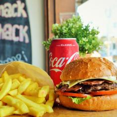 Surf Club Burger with House-made beef patty, bacon, cheese, tomato, lettuce & Shack Aioli. Chips and a can of coke