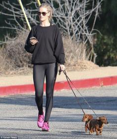 
                    
                        Dog fan: Rosie  Huntington-Whiteley keeps an eye on her phone as she walks her dogs in LA
                    
                