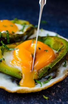 Eggs Baked in Avocado served on a naturally formed white plate. No oven needed! The yolks are perfectly soft unlike the oven baked versions. | giverecipe.com | #avocado #avocadorecipes #eggrecipes #healthyrecipes #breakfast #eggsbakedinoven