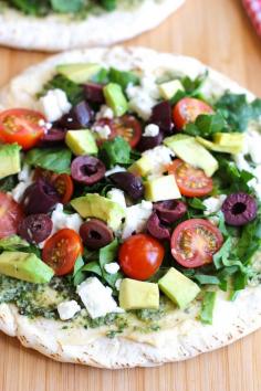Open Faced Mediterranean Pita Sandwich: hummus and pesto on a pita with baby spinach, sweet cherry tomatoes, sliced kalamata olives, salty feta, and creamy avocados. Sounds healthy and delicious.