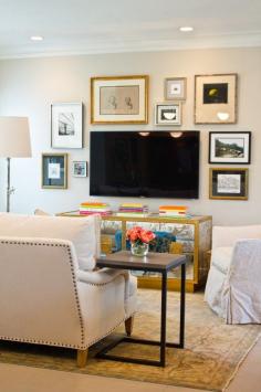 balanced gallery wall with gold frames around TV (via Material Girls) I want that stool!!!!